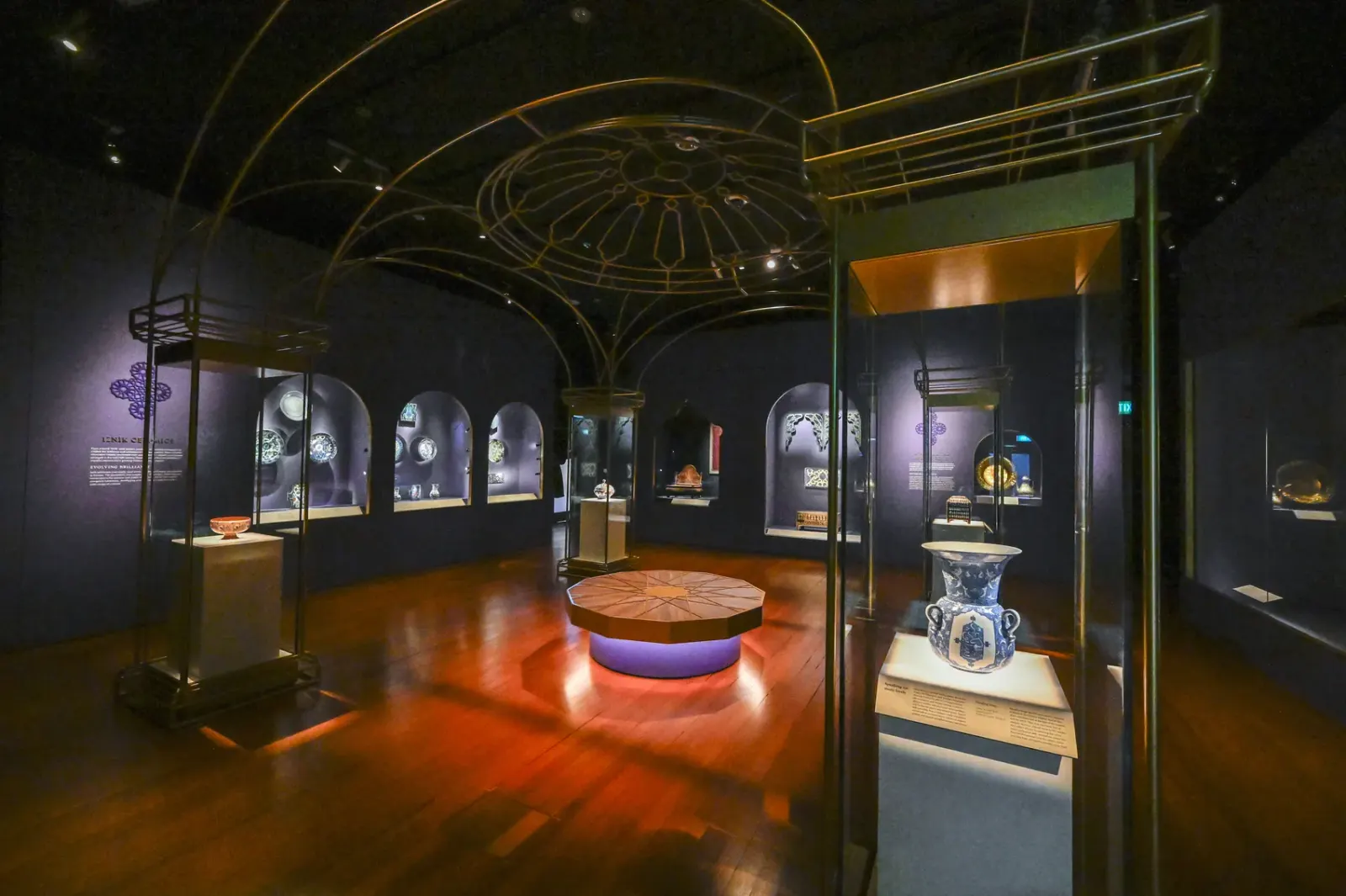 A domed gallery with a gilded armature overhead, arched niches around the walls and a circular central case