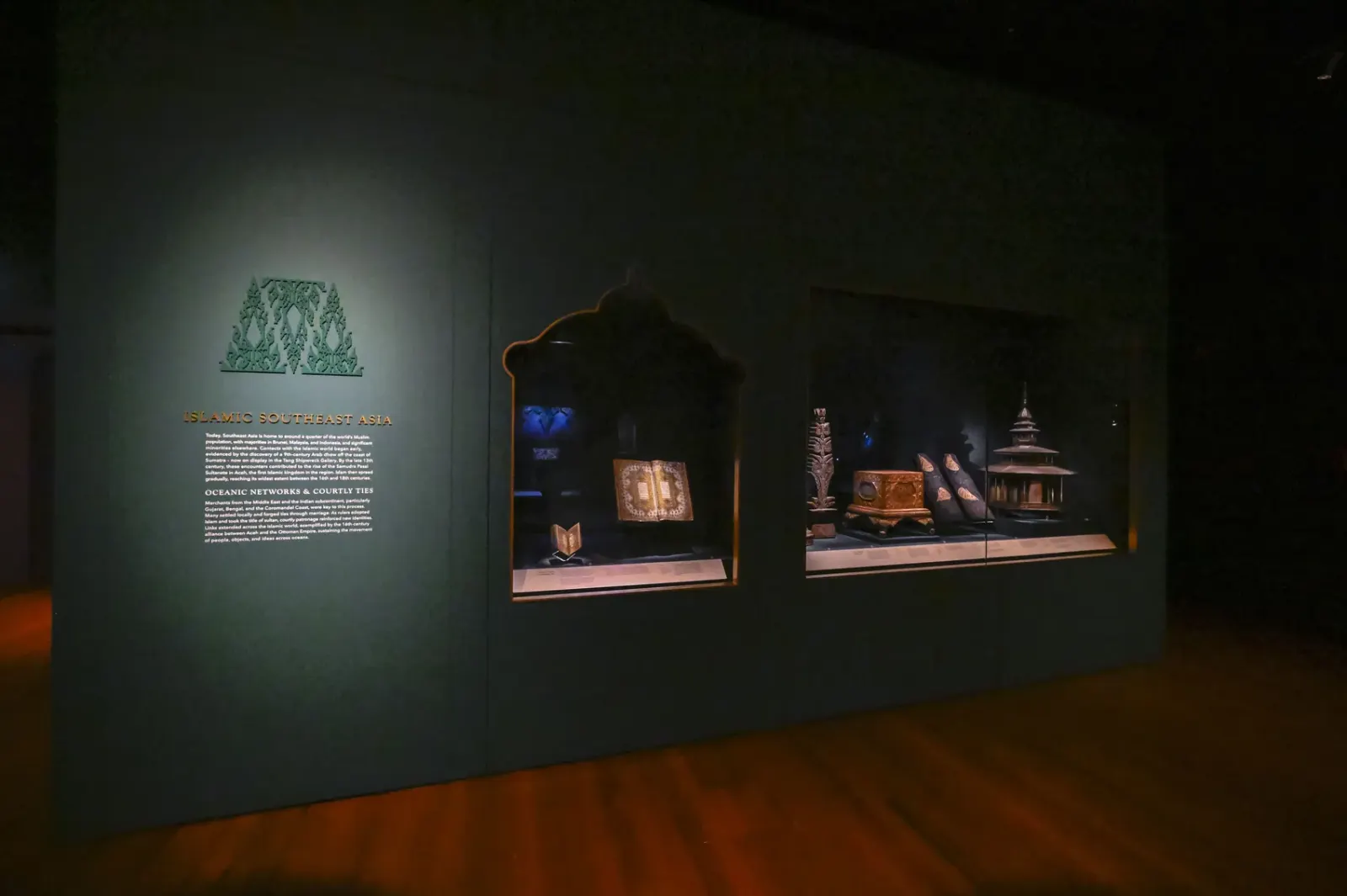 The Islamic Southeast Asia gallery: a deep green wall with a gold title and arched cases holding a mosque model and manuscripts
