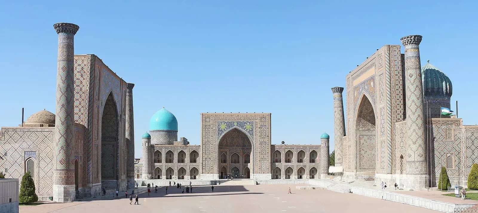 Registan square in Samarkand, three tiled madrasahs with turquoise domes under a clear blue sky
